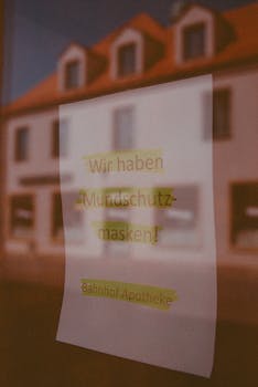 Close-up of a paper sign on a glass window with building reflection, in German text.