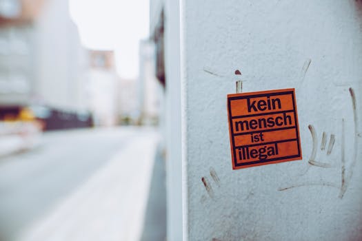 Close-up of a sticker with 'kein mensch ist illegal' on an urban street corner.