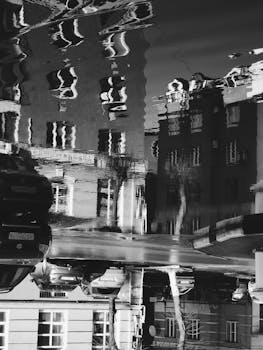 Monochrome cityscape reflecting in a puddle on a rainy street in Ryazan, Russia.